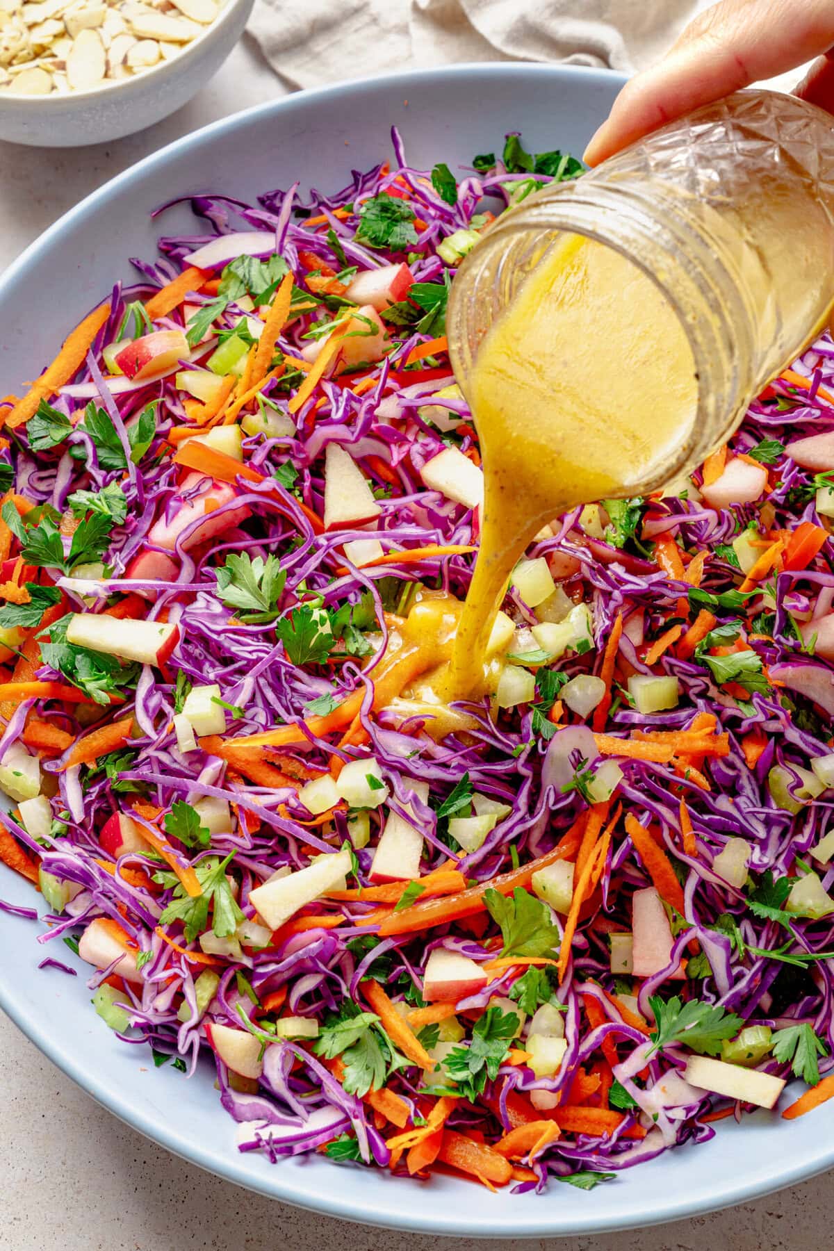 Pouring the dressing over the bowl of salad.