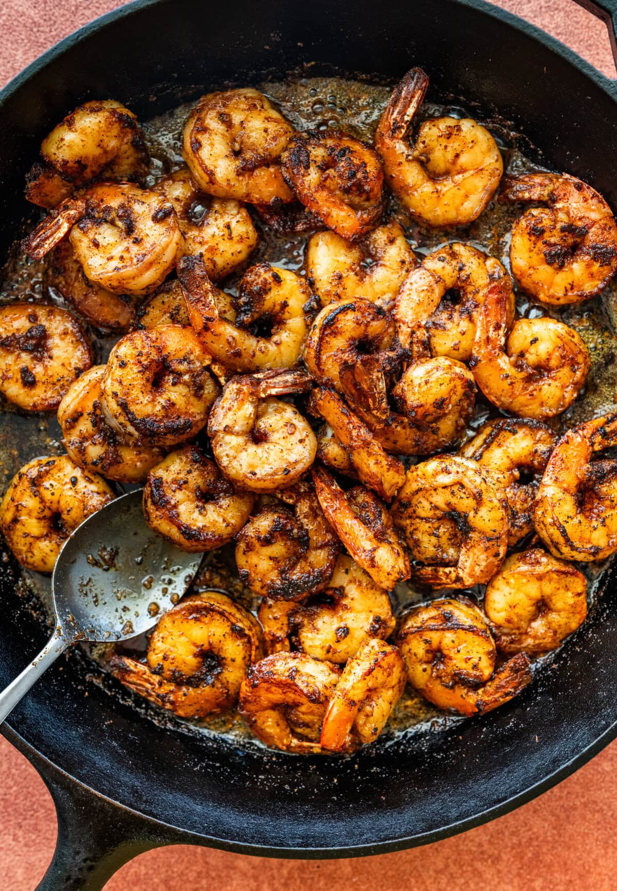 Spoon mixing the shrimp in the skilelt.