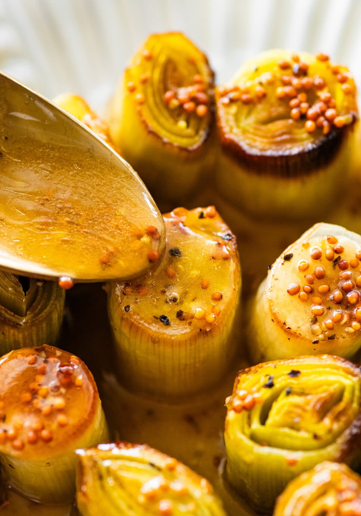 Spoon dousing leeks with pan juices.