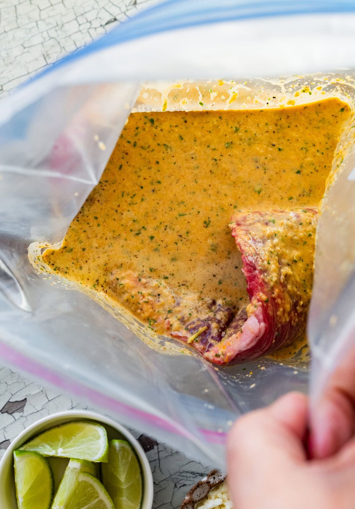Steak submersed in marinade in a plastic ziptop bag.