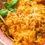 Chicken and orzo in a bowl garnished with basil, with a fork placed in it.