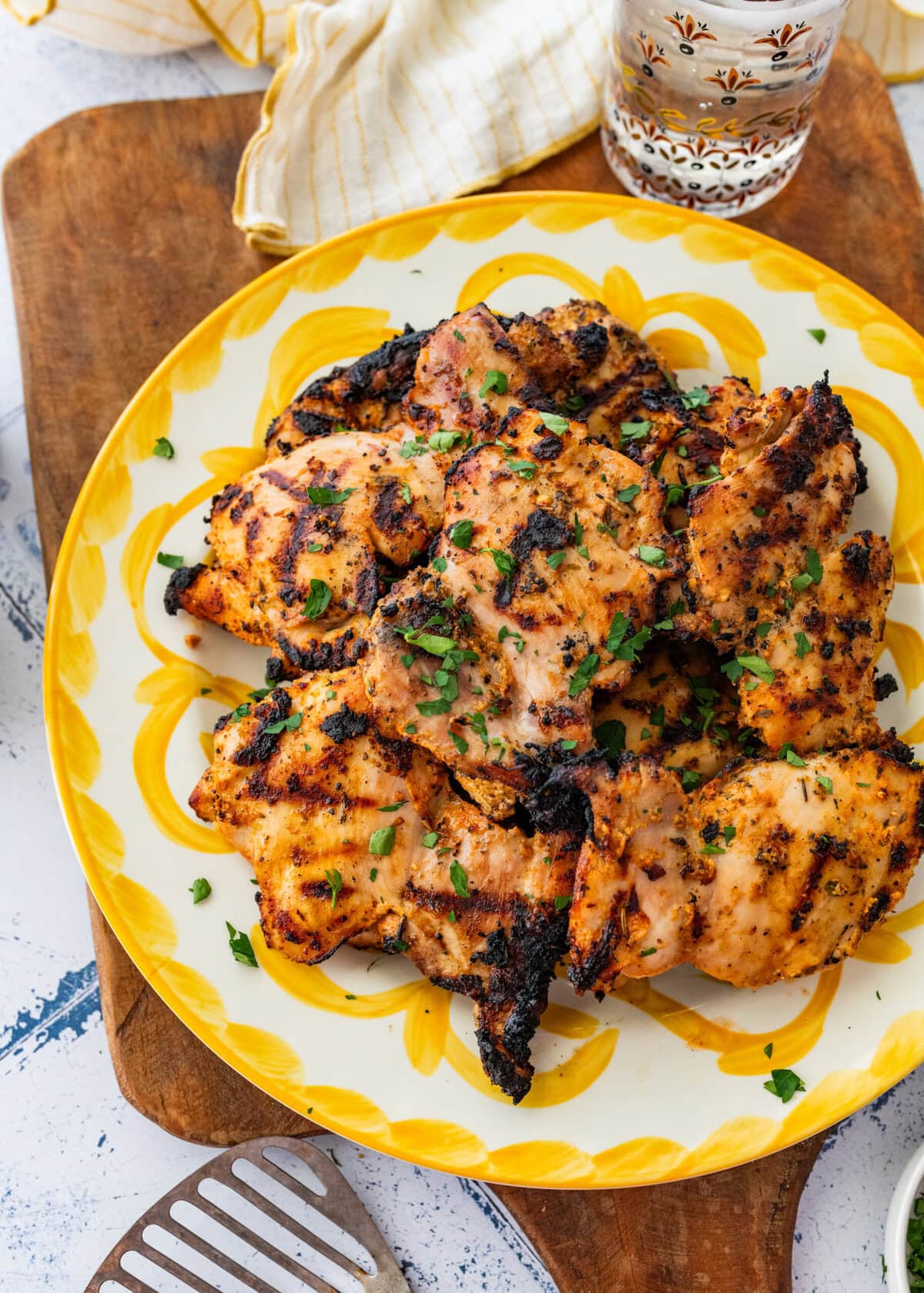 Chicken on a serving dish with garnish, and more sides surrounding.
