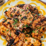 Chicken on a serving dish with garnish.