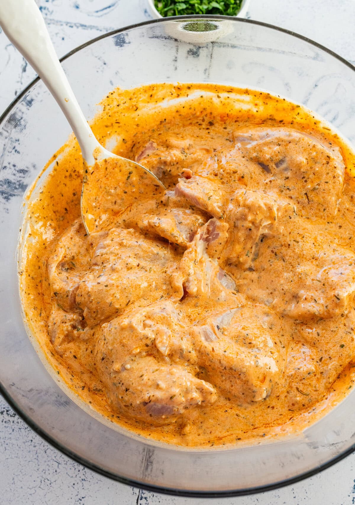 Chicken in a bowl of marinade after mixing.