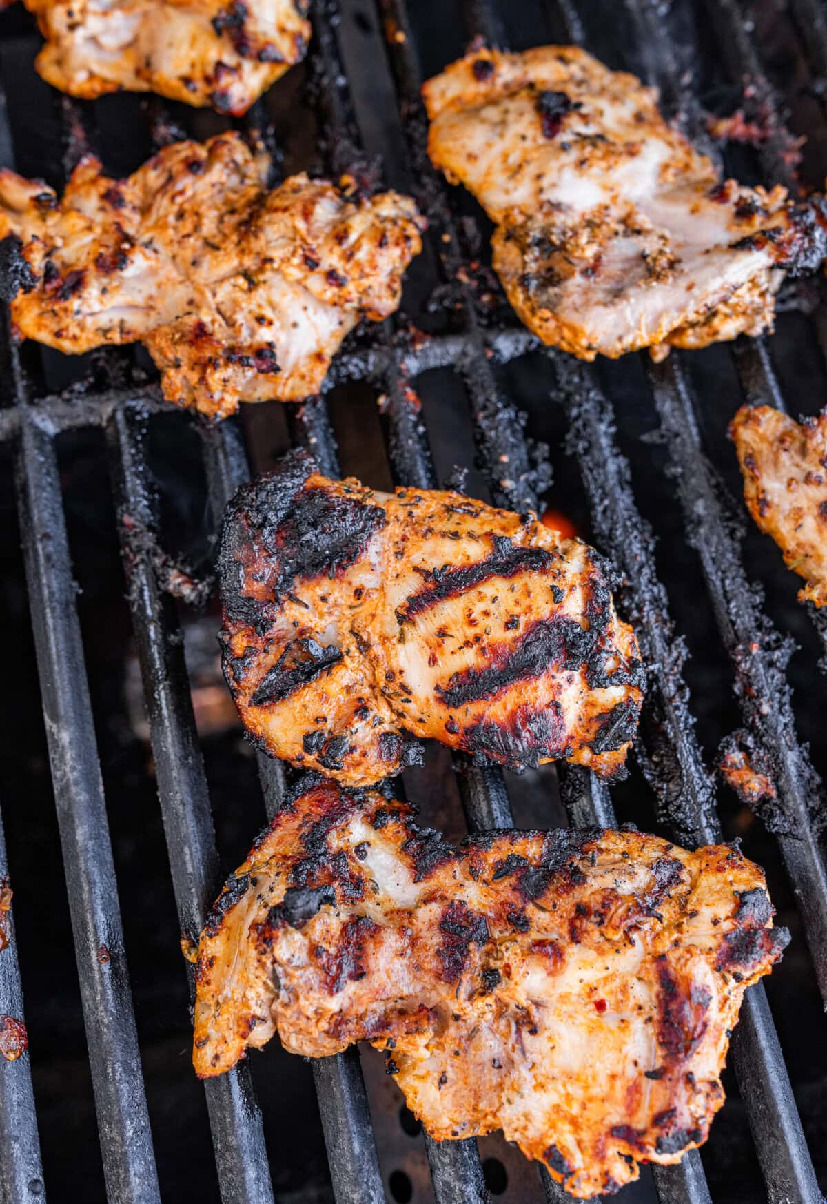 Chicken on a lit grill after cooking on one side and flipping.