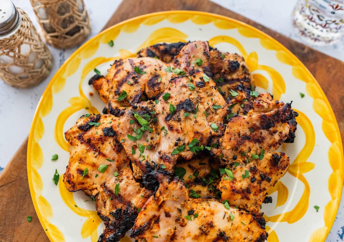 Chicken on a serving dish with garnish, and more sides surrounding.