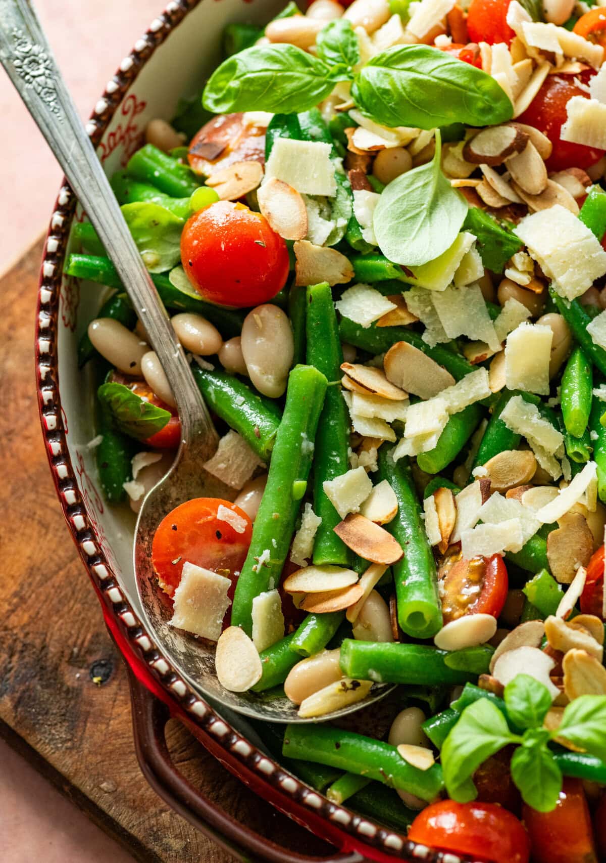 Green bean salad in a serving bowl with serving utensil resting in it.
