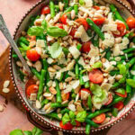 Green bean salad in a serving bowl with serving utensil resting in it.