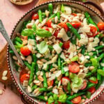 Green bean salad in a serving bowl with serving utensil resting in it.