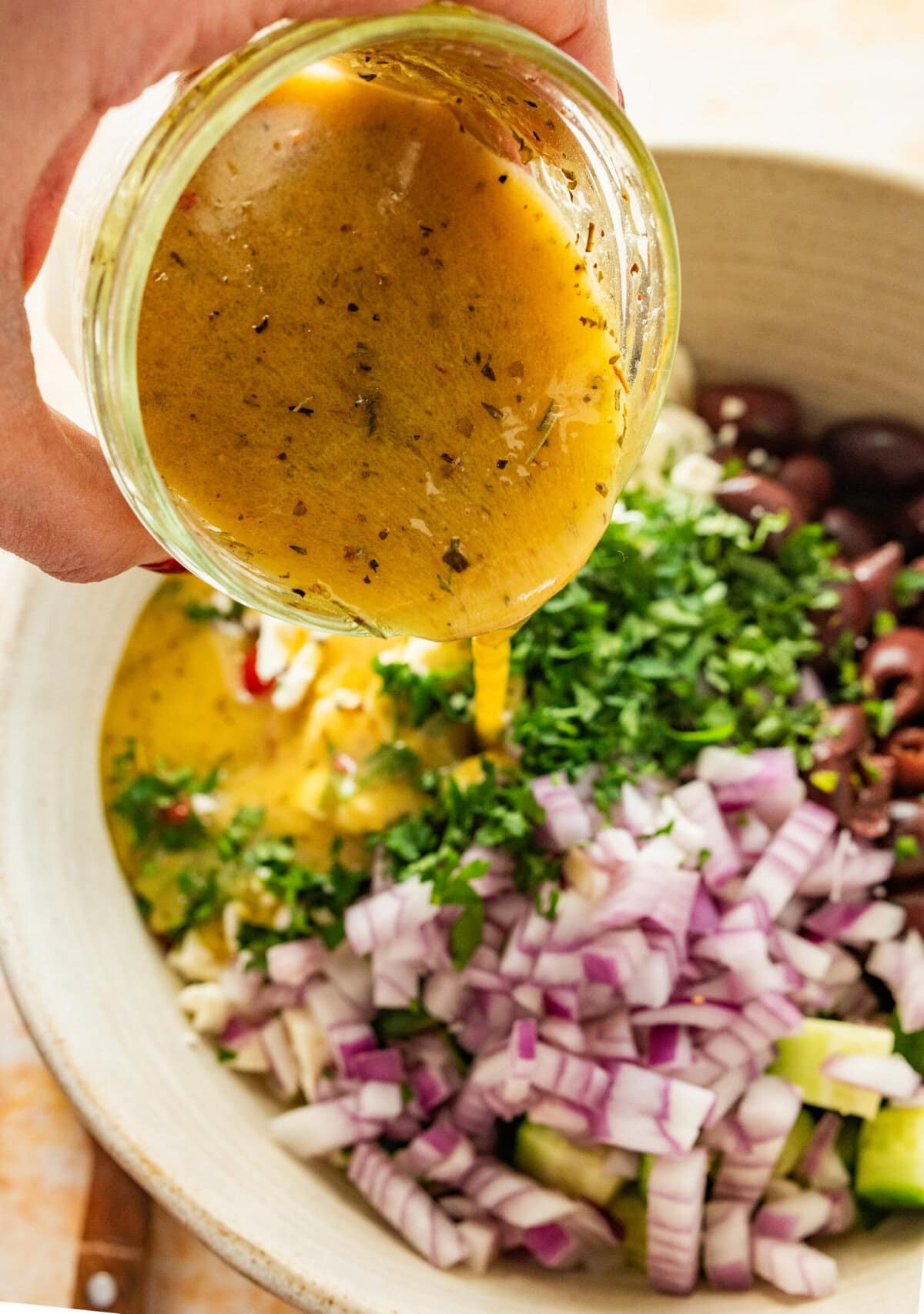 Dressing being poured over the salad bowl.