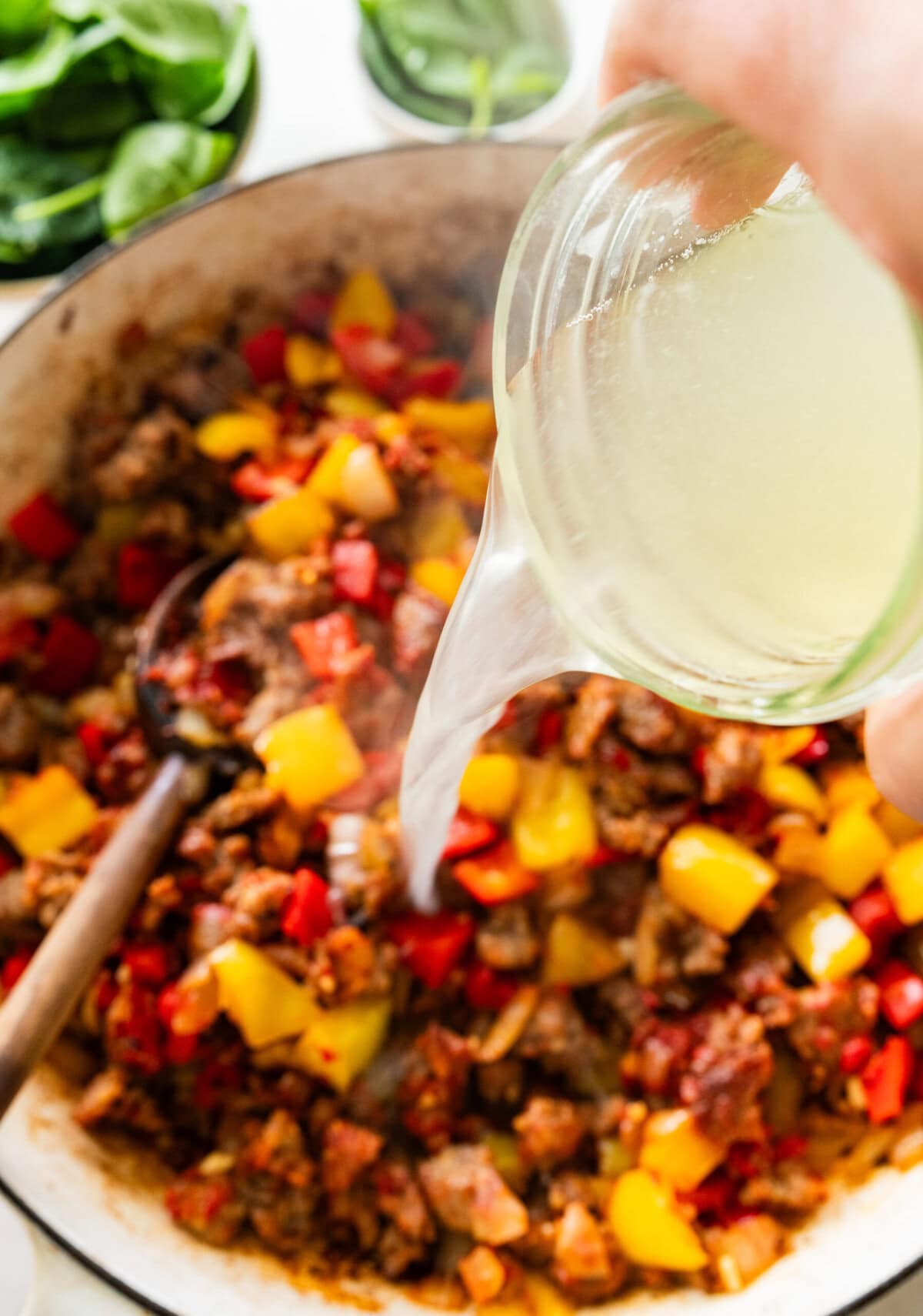 Pouring reserved pasta water into the pot.