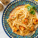 A single serving of scallop pasta on a plate with garnish.