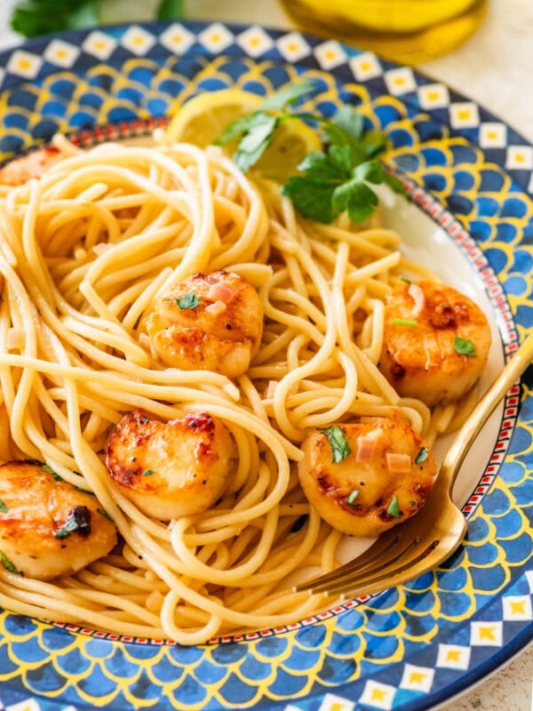 A single serving of scallop pasta on a plate with garnish.