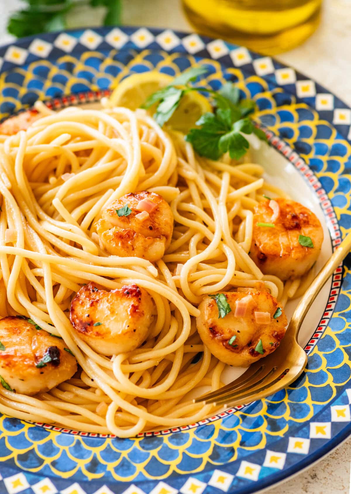 A single serving of scallop pasta on a plate with garnish.