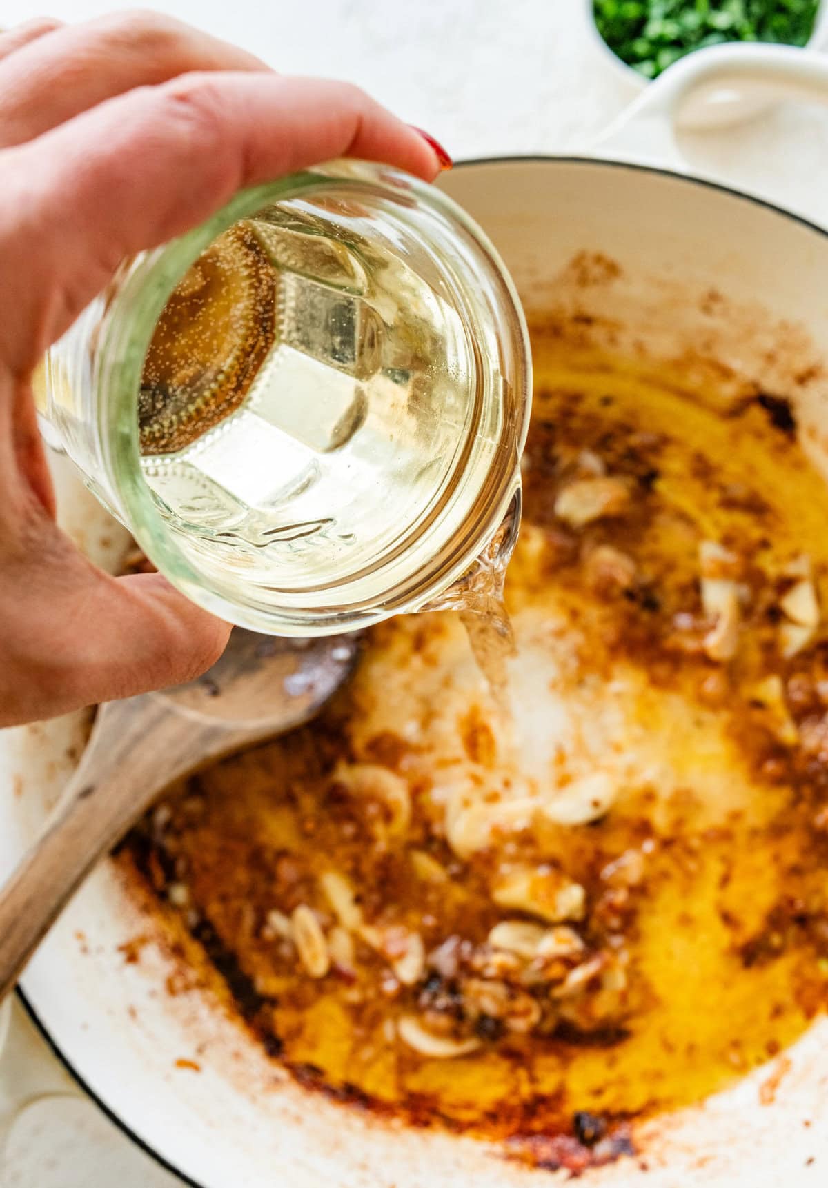 White wine being poured into the skillet.