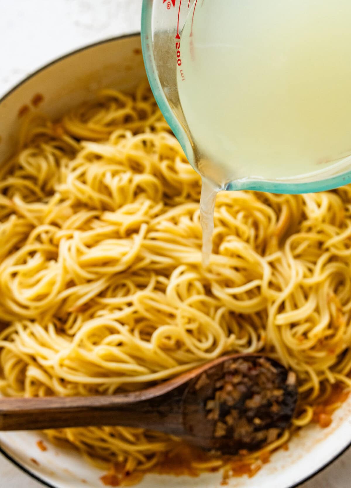 Pasta water being poured over the pasta.