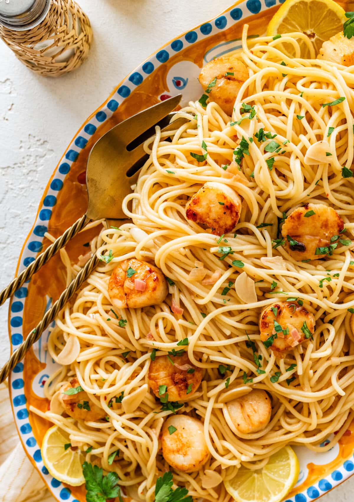 Scallop pasta on a serving plate with utensils.