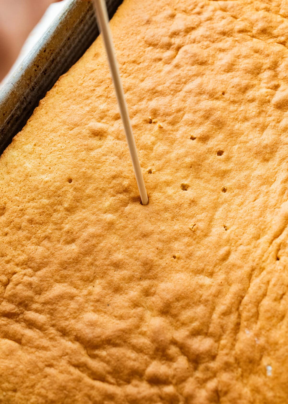 Poking holes all over cooled cake.