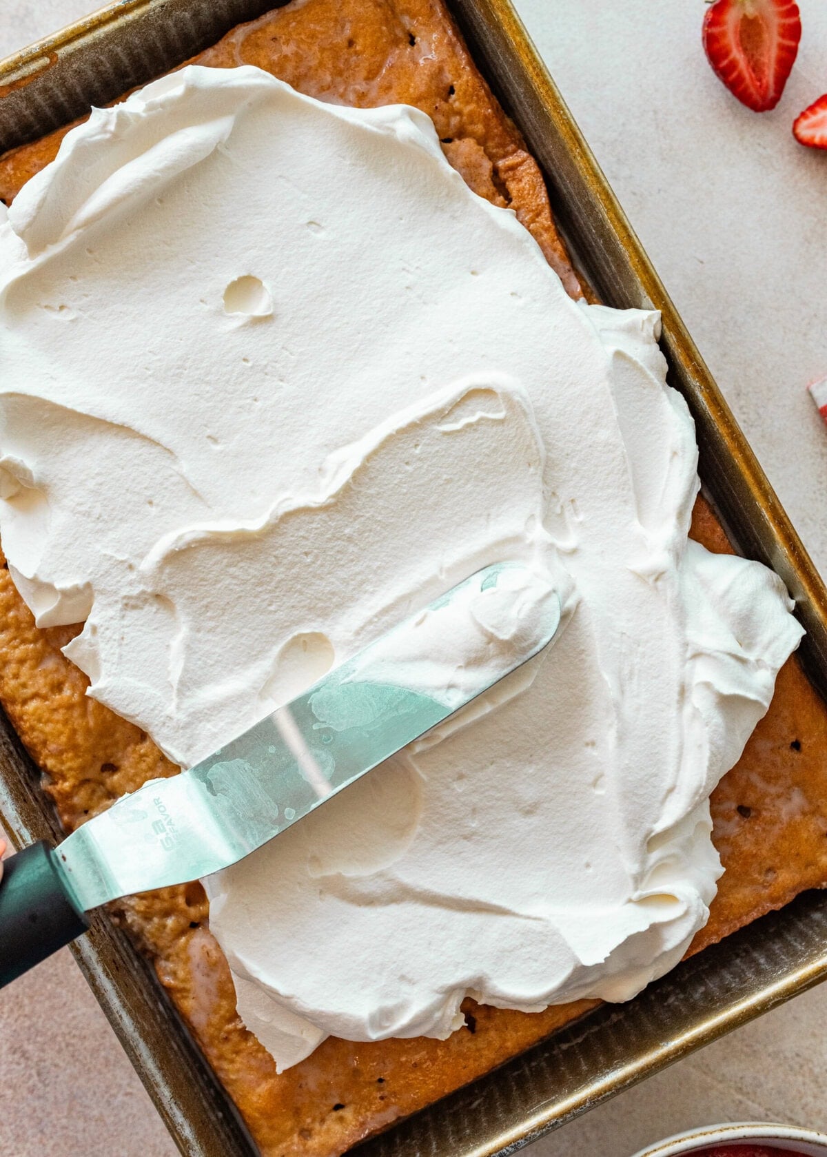 whipped cream being spread over cake.