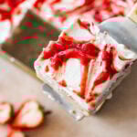 a slice of strawberry tres leches cake, shown from the top, plated with a spoon and more ingredients nearby.