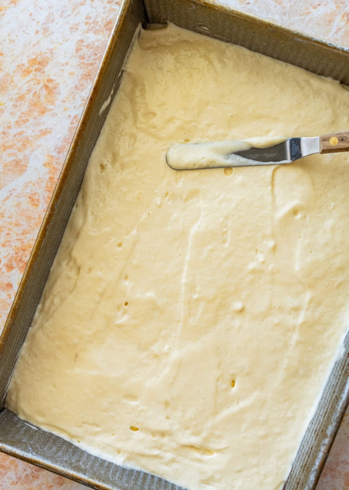 Batter in a baking pan being smoothed out.