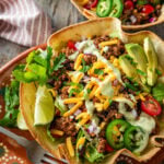 Two fully dressed taco bowls with garnish.