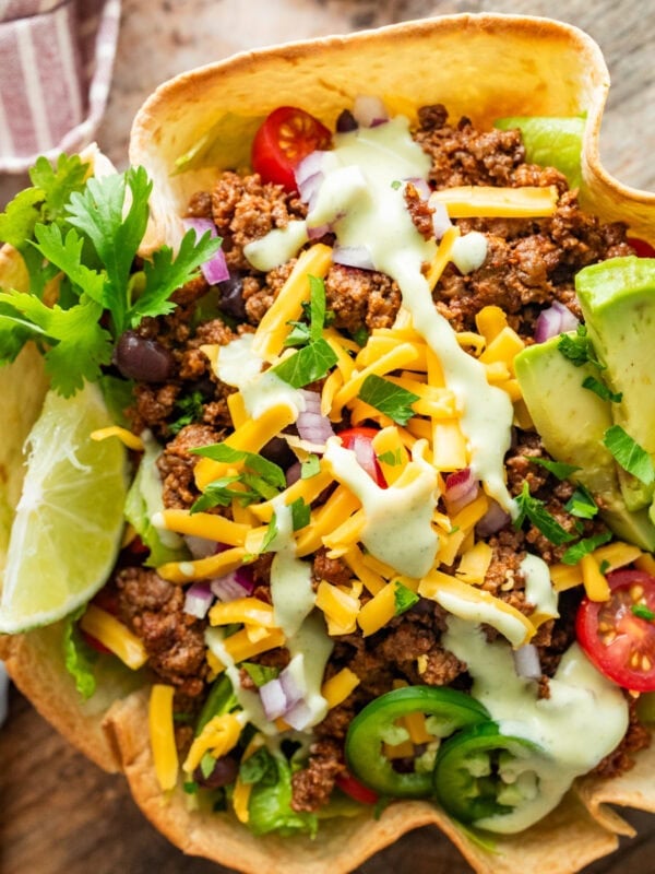 A fully dressed taco bowl with garnish.