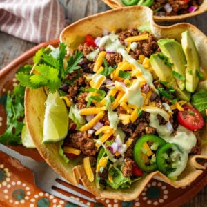 A fully dressed taco bowl with garnish.