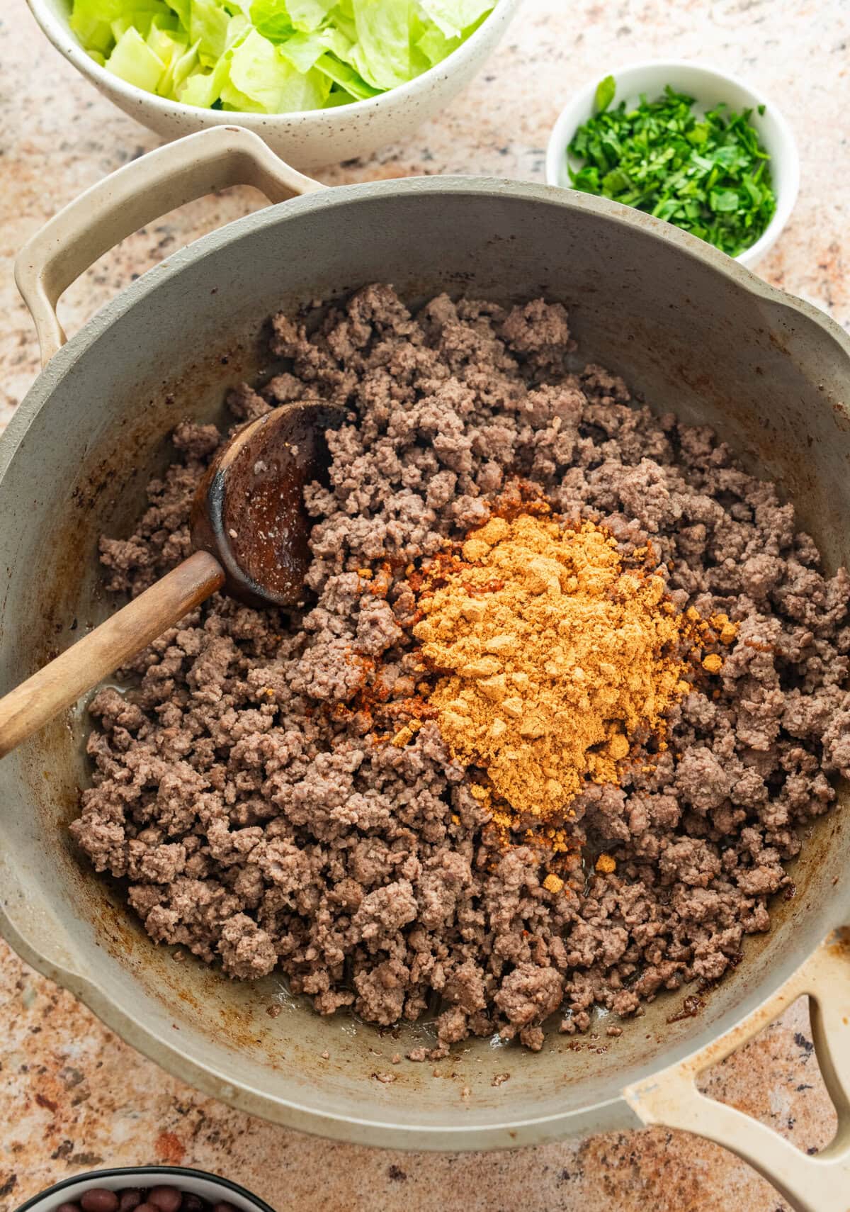 Taco seasoning being mixed into ground beef.