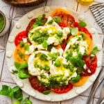 A plate of tomato burrata salad with garnish, placed next to additional ingredients.