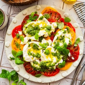 A plate of tomato burrata salad with garnish, placed next to additional ingredients.