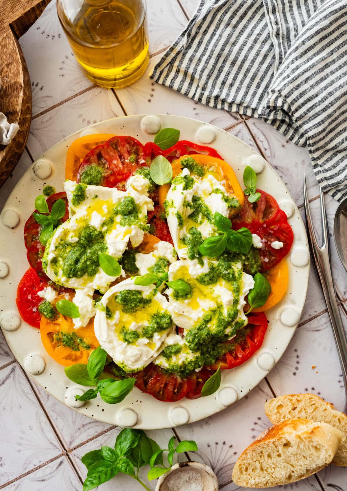 A plate of tomato burrata salad with garnish, placed next to additional ingredients.