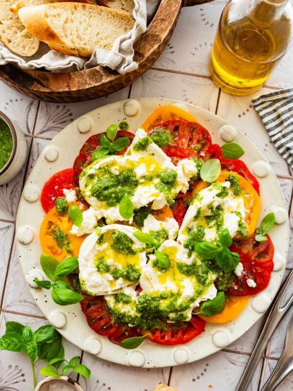 A plate of tomato burrata salad with garnish, placed next to additional ingredients.