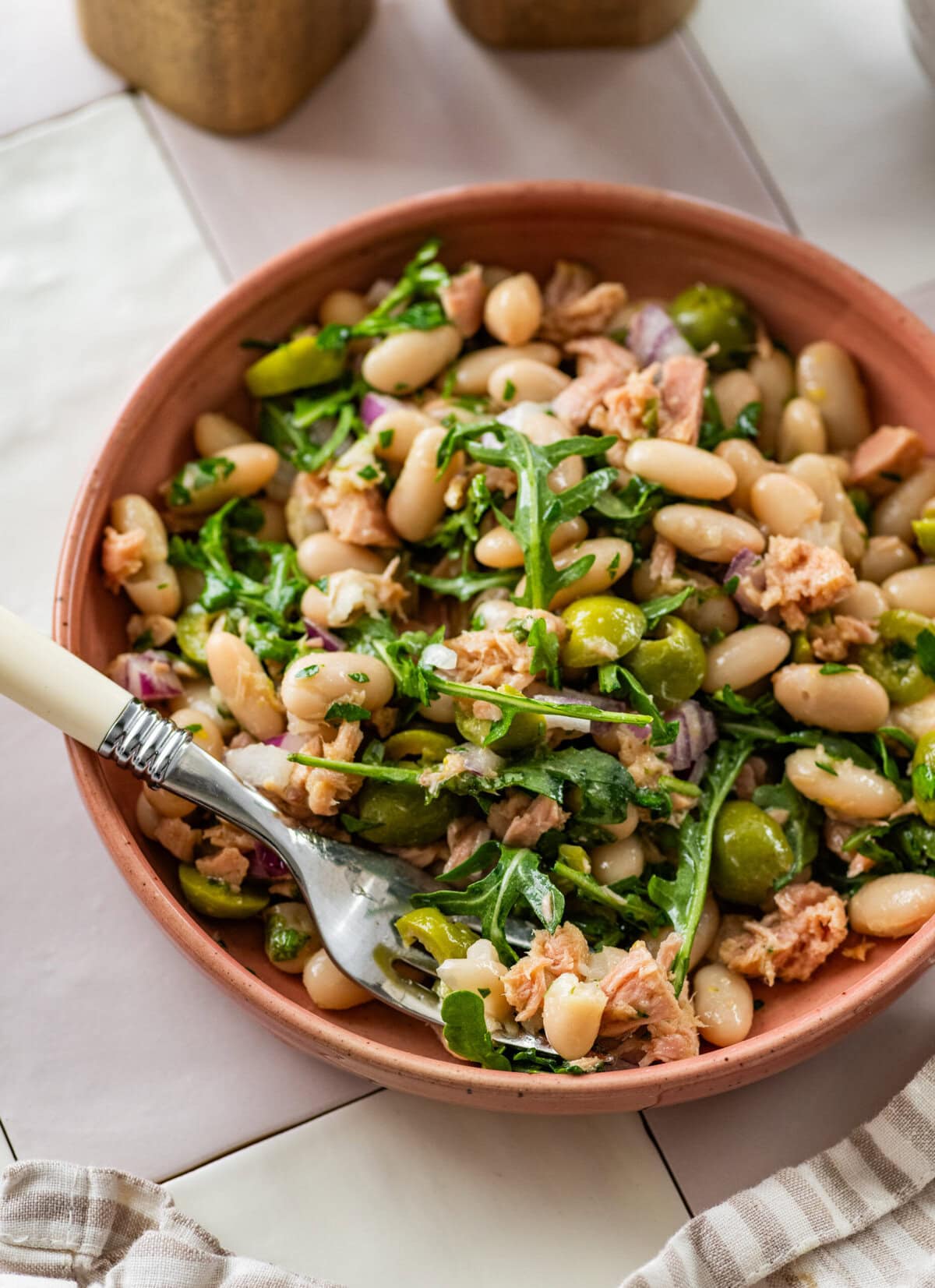 Tuna and white bean salad in a serving bowl with garnish and a serving spoon.
