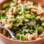 Tuna and white bean salad in a serving bowl with garnish and a serving spoon.