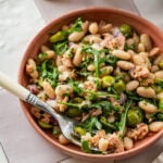 Tuna and white bean salad in a serving bowl with garnish and a serving spoon.