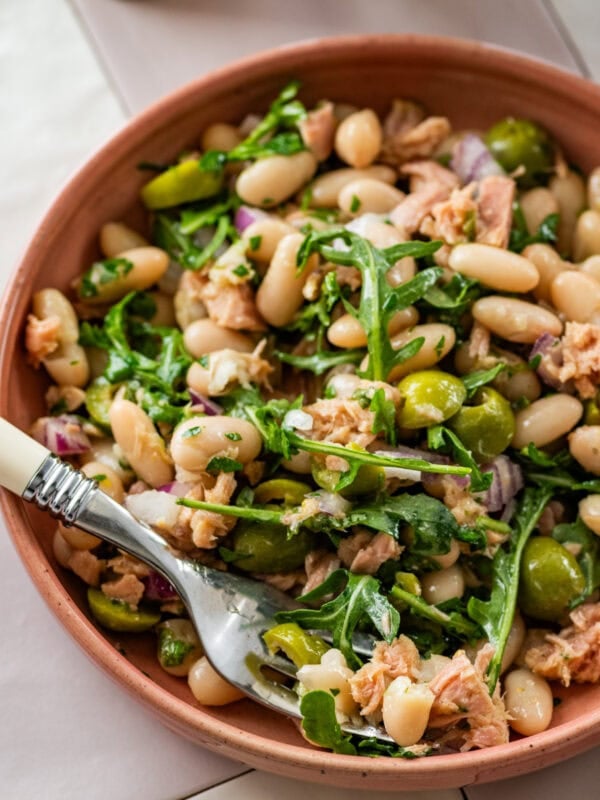 Tuna and white bean salad in a serving bowl with garnish and a serving spoon.