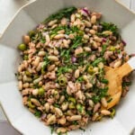 Tuna and white bean salad in a serving bowl with garnish and a serving spoon.