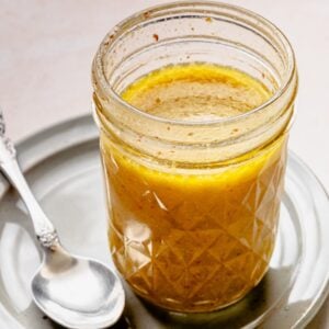 A jar of the dressing after completely combined with a spoon nearby.
