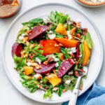 A plate of beet salad with utensils and more ingredients nearby.