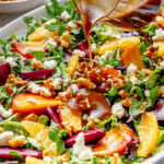 Pouring a jar of dressing over the prepared salad.