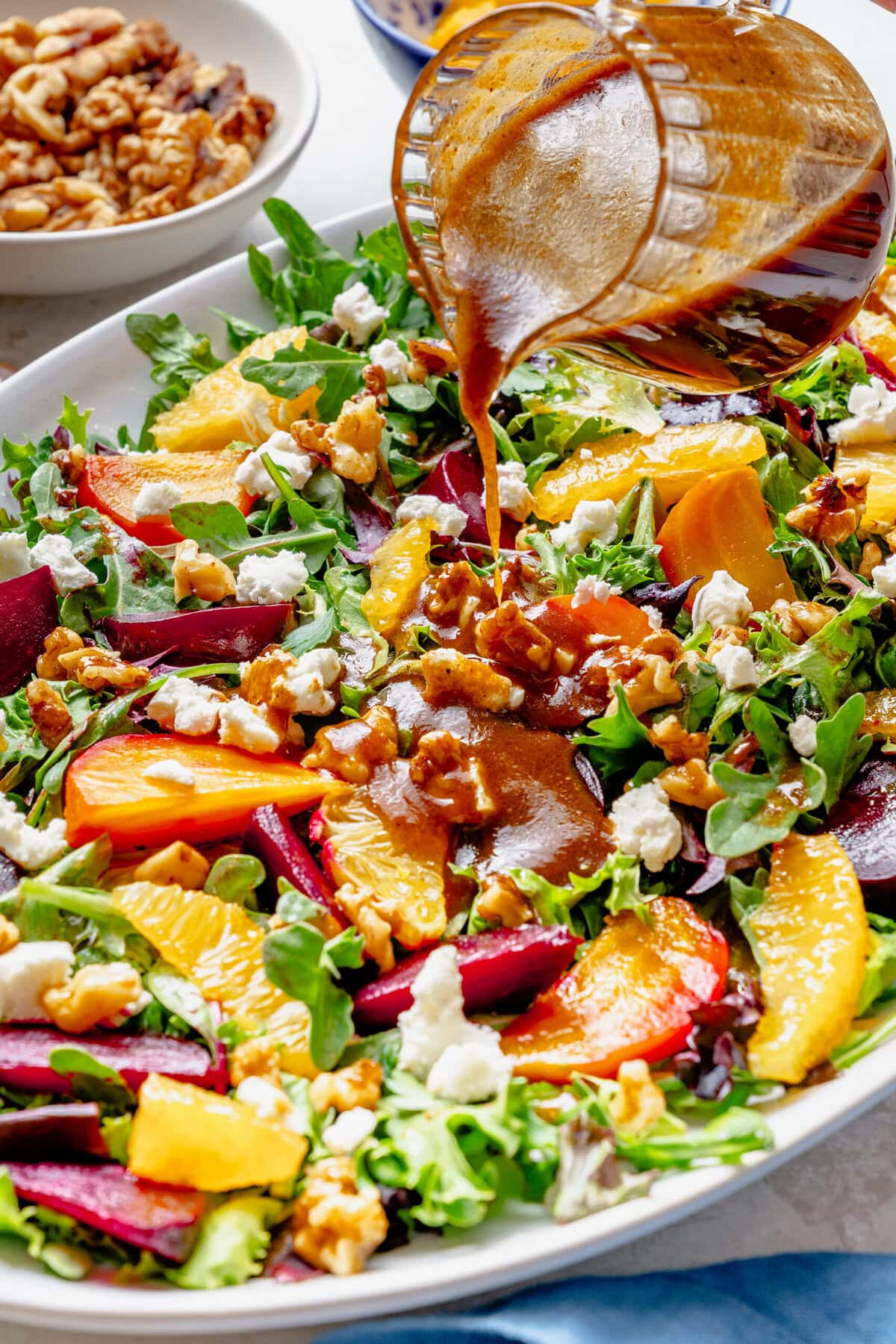 Pouring a jar of dressing over the prepared salad.