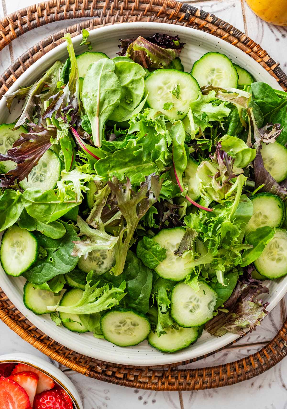 tossing the lettuce, mint, and cucumber in a bowl.