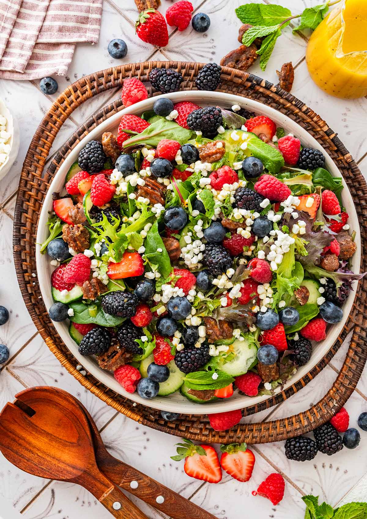 white plate of berry goat cheese salad on a wicker tray.