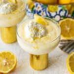 One serving of lemon mousse in a bowl with garnish and more ingredients in the background.