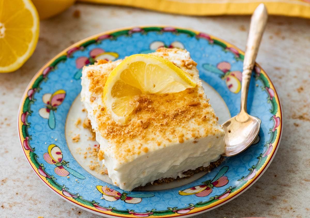 frozen lemon bar on a blue plate garnished with a lemon slice.