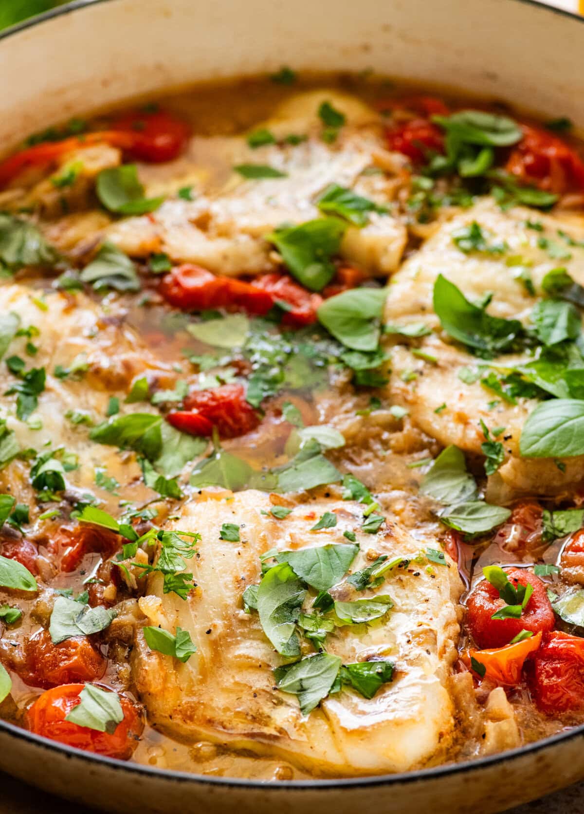 Italian poached fish in a skillet with garnish.