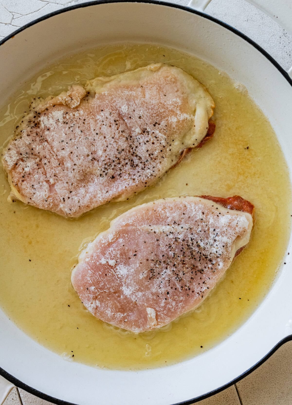 chicken in a pan after dredging and seasoning.
