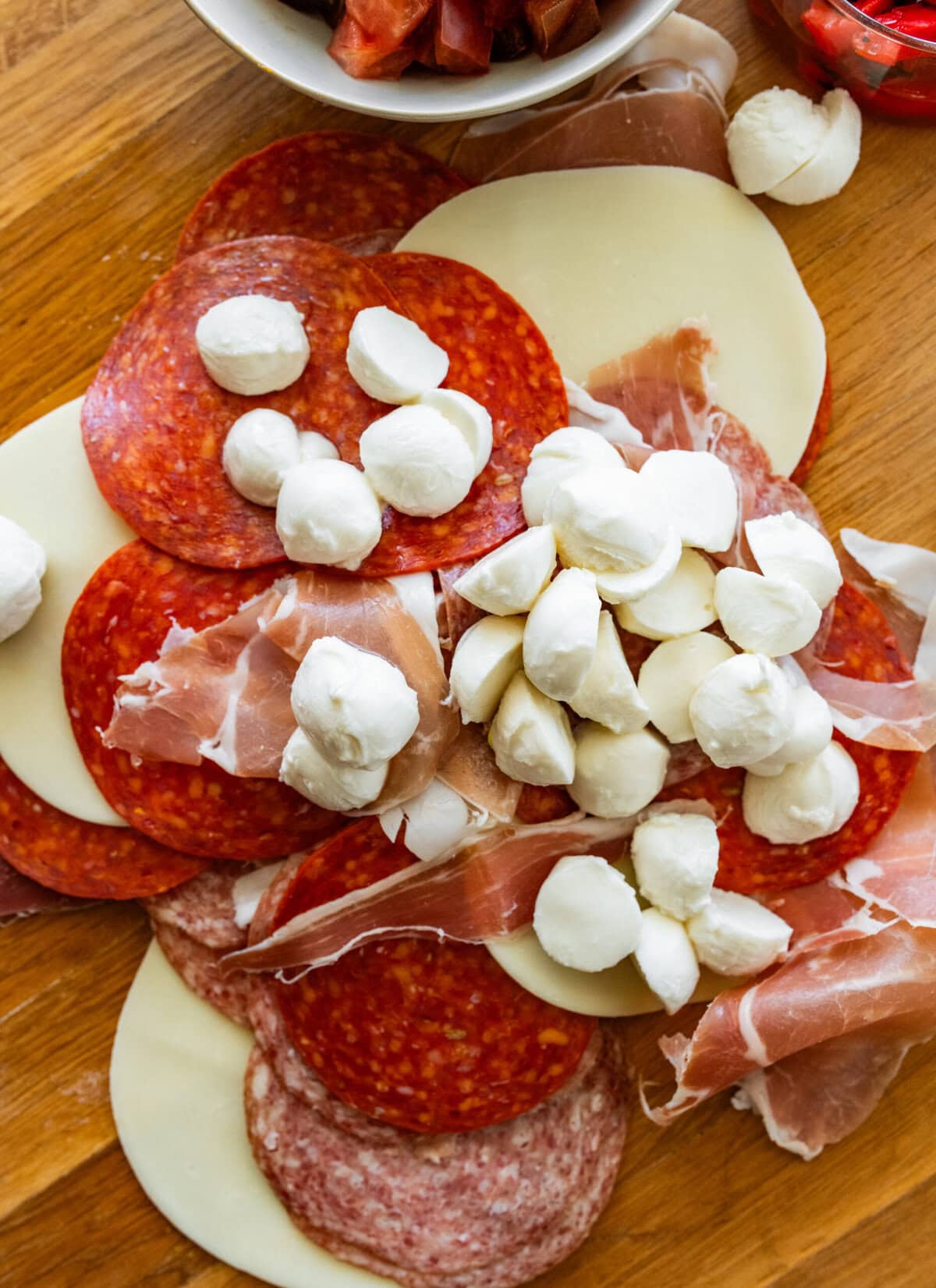 Deli meats and cheeses stacked on a cutting before before cutting.