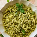 a large bowl of creamy pesto pasta garnished with basil.
